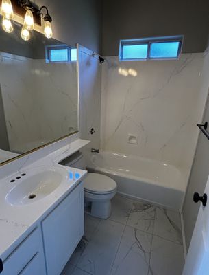 Full bathroom refinished with faux marble on tub surround, countertop, and floor