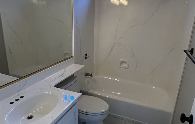 Full bathroom refinished with faux marble on tub surround, countertop, and floor