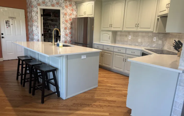 Full kitchen with sage green refinished cabinets, white countertops, and subway tile backsplash