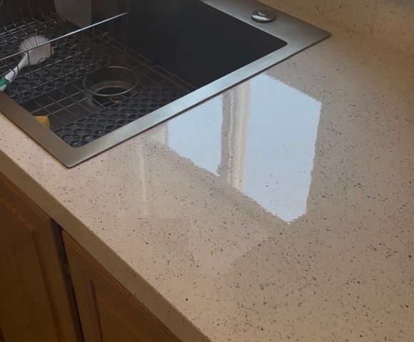 Kitchen countertop resurfaced in a glossy white speckled stone-look finish around a stainless sink