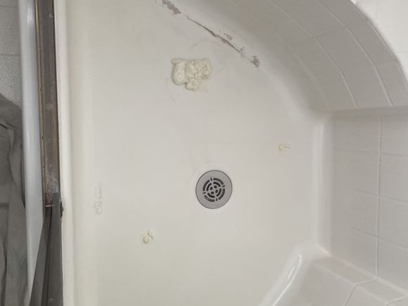 Cracked and peeling corner shower pan before repair
