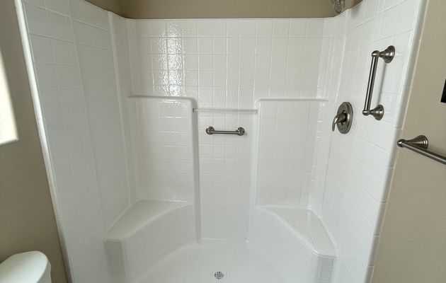 Refinished fiberglass shower stall restored to a bright white finish