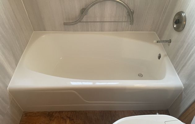 Refinished white bathtub with a glossy finish next to a grab bar