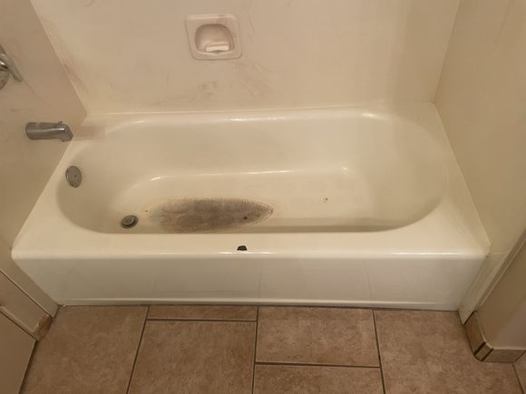 Worn bathtub with a white tile surround before refinishing