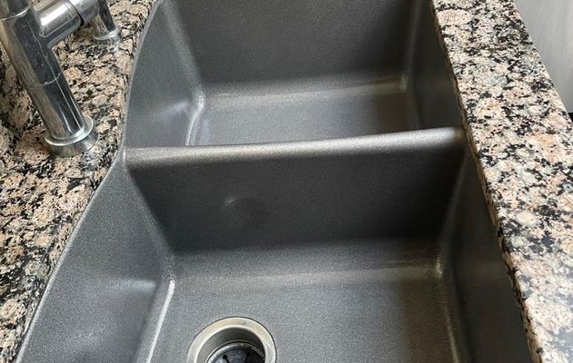 Kitchen sink refinished in dark charcoal gray with granite countertop