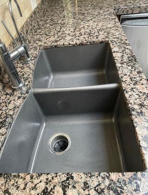 Kitchen sink refinished in dark charcoal gray with granite countertop