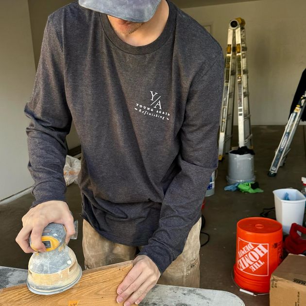 Young Again Refinishing technician sanding cabinet surface